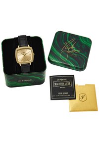 Montre carrée en or avec un bracelet en cuir noir dans une boîte en métal marbrée verte. Comprend une carte noire portant l'inscription "MACHINE LUXE" et une carte dorée texturée.