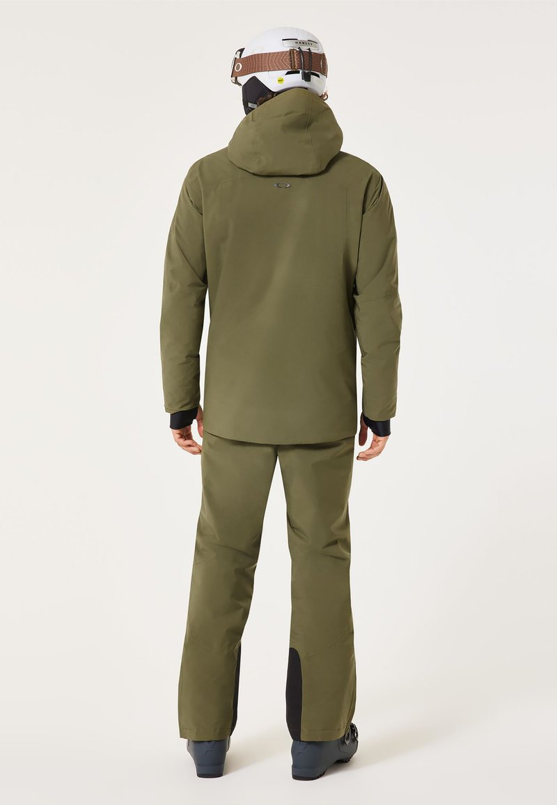 Olivgrüne wasserdichte Skijacke und Hose, ausgestattet mit einer Kapuze, langen Ärmeln und schwarzen Akzenten an den unteren Beinen der Hose und an den Bündchen.