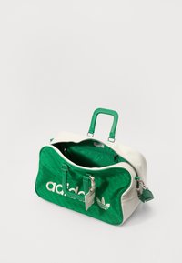 Grønn og hvit duffelbag med teksturert finish, som har en stor "adidas"-logo, doble håndtak og en intern lomme.
