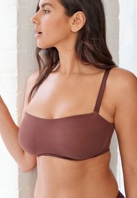 Braun trägerloser BH mit glatter Textur, ausgestattet mit verstellbaren Schulterträgern und einem schlichten Design, geeignet für verschiedene Outfits.