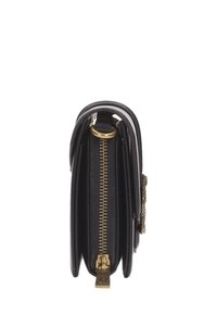 Cartera de cuero negro con cremallera dorada, múltiples compartimentos y un detalle de anillo dorado sobre un fondo blanco.