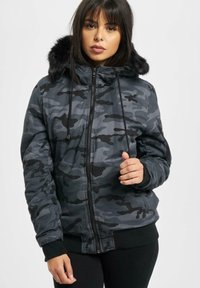 Camo-jakke i grå og sorte mønstre, med lynlås foran, snoretræk ved hætten og falsk pelskant. Ribstrikkede manchetter og kant for varme.