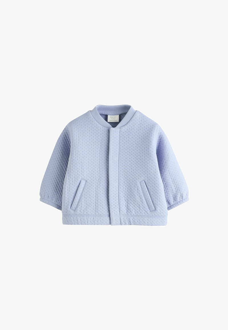 Veste bébé matelassée bleu clair à manches longues, poches avant et col rond, posée à plat sur un fond blanc.