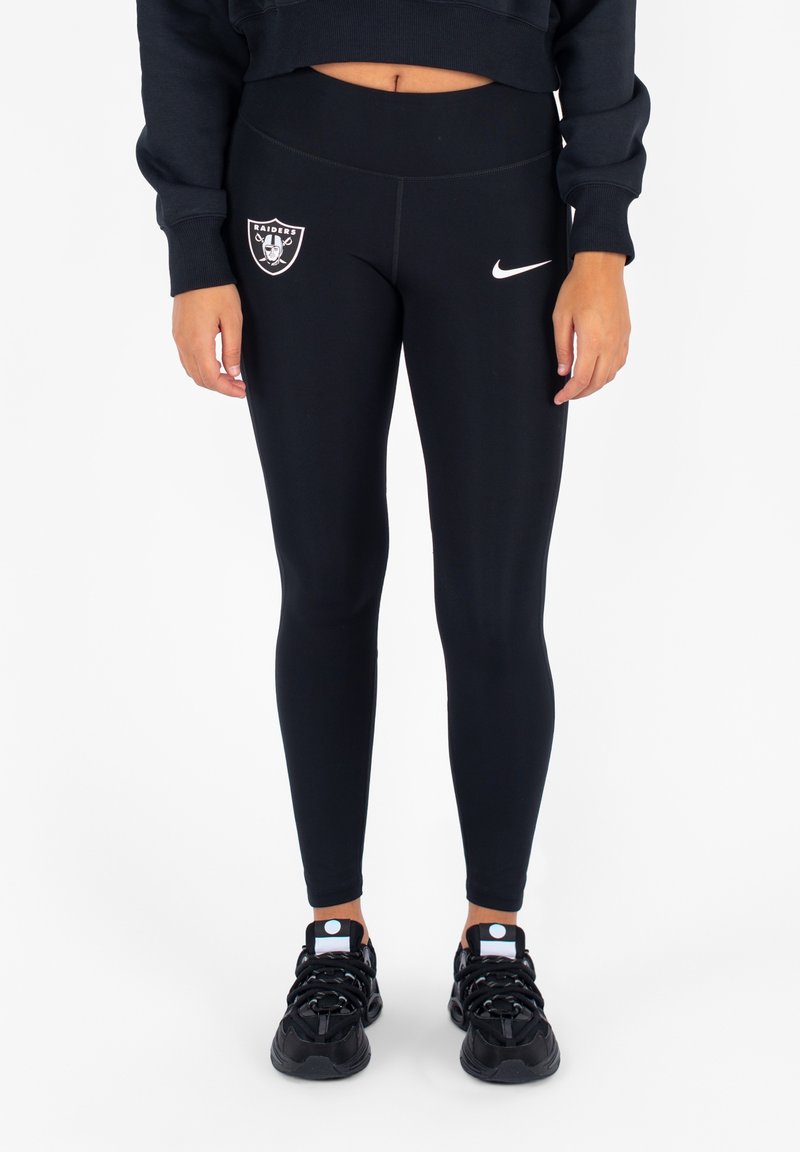 Zwarte leggings met een Oakland Raiders-logo en een witte Nike swoosh. Rekbaar materiaal met een aansluitend ontwerp, gecombineerd met zwarte sneakers.