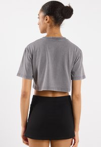 Grå kortermet t-skjorte med rund hals, sammen med et svart, tettsittende miniskjørt. Myk, slitt tekstur og enkelt design.