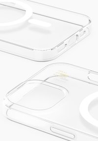 Clear phone case with rounded edges, cutouts for camera and buttons, and a circle for magnetic charging. Text on inside reads "IDEAL OF SWEDEN."