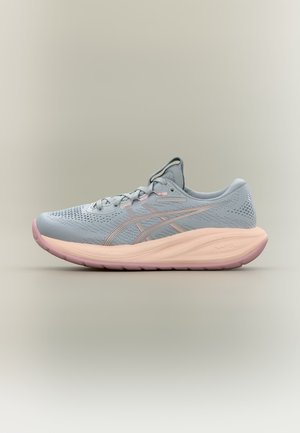 Zapatilla de running azul clara con suela y cordones rosas, parte superior de malla transpirable y entresuela acolchada, mostrada de lado sobre fondo neutro.