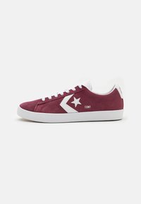 Burgundy suede sneakers with white rubber sole, featuring a star logo and chevron design on the side, and white laces.