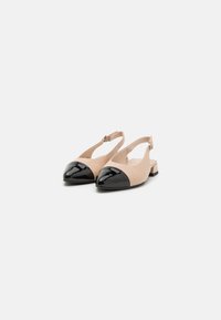 Nagie buty typu slingback z czarnym lakierowanym czubkiem. Płaska pięta, regulowany pasek wokół kostki i gładka faktura. Prosty design.