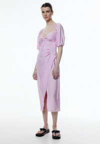 Roze jurk met pofmouwen, een aansluitend lijfje, knoopdetail aan de voorkant en een middellange rok met een zijnaanpassing. Gladde textuur.