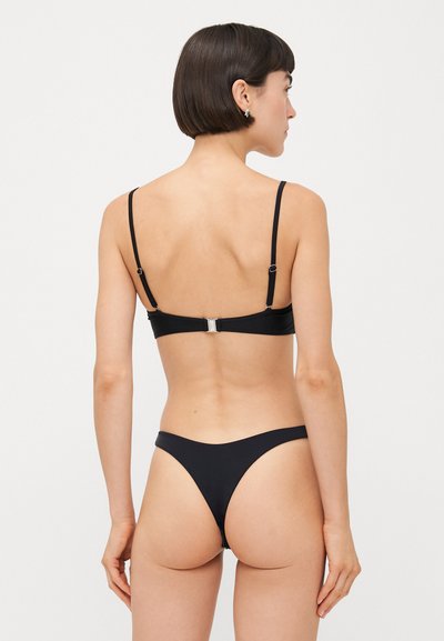 Melnas bikini komplekts ar minimālistisku dizainu, regulējamām siksnām, aizdari aizmugurē un bezšuvju bikini apakšbiksēm.