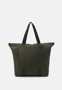 Grand sac fourre-tout vert foncé avec poignées noires, poche rectangulaire à l'avant et fermeture éclair en haut sur fond blanc.