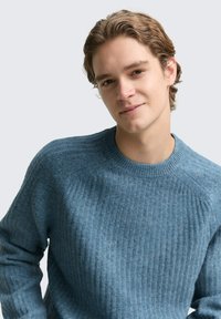 Niebieski sweter z prążkowanego dzianiny z okrągłym dekoltem i długimi rękawami, charakteryzujący się teksturowaną powierzchnią i subtelnymi różnicami w odcieniach koloru.