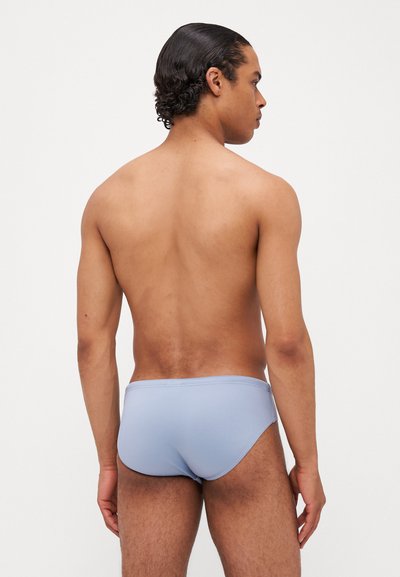 Modri kopalke z gladko teksturo, nizkim krojem in elastičnim pasom, zasnovane za udobje in gibanje.