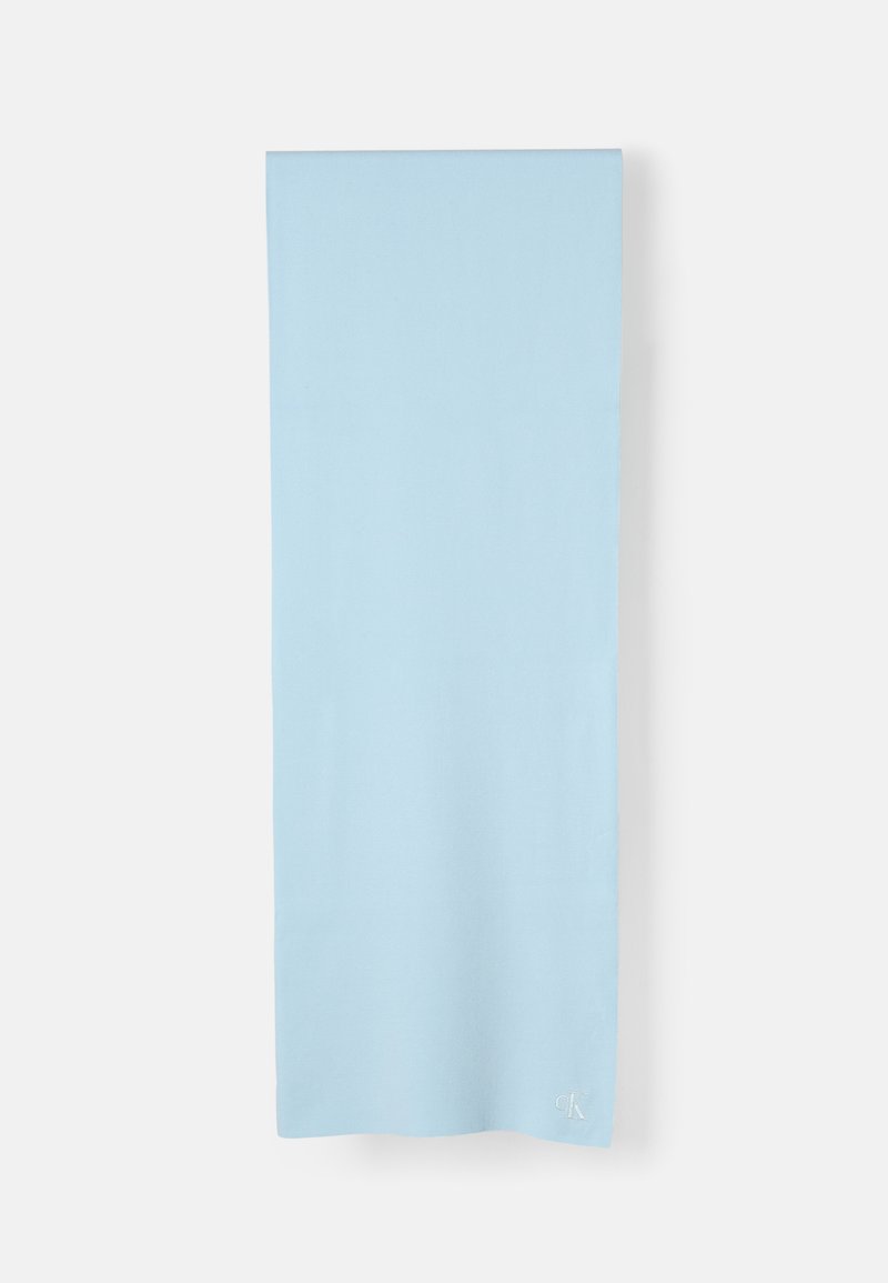 Écharpe en coton bleu clair avec une texture lisse, de forme rectangulaire, et un petit logo brodé dans le coin inférieur.