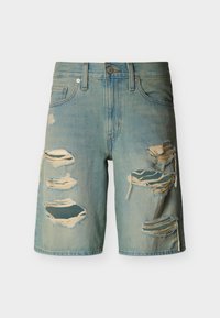 Ανοιχτό μπλε τζιν σορτς με πολλές μεγάλες φθορές στα μπροστινά μηριαία μέρη και ξεφτισμένες άκρες, κλείσιμο με κουμπί και φερμουάρ.