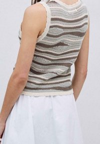 Gebreid mouwloos topje met een gestreept ontwerp in beige en bruine tinten, afgewerkt met een gegolfde halslijn en een textuur die licht van gewicht is.