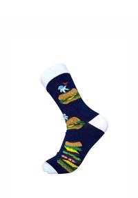 Laivastonsininen sukka valkoisella varrella ja kärjellä, jossa astronautit pitävät lippuja seisten suurten, kerrostettujen hampurilaisten päällä, joissa on salaattia, tomaattia ja juustoa.