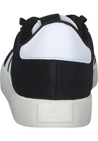 Scarpe sportive in bianco e nero con una tomaia liscia e testurizzata, colletto imbottito e suola in gomma con un logo impresso sul tallone.
