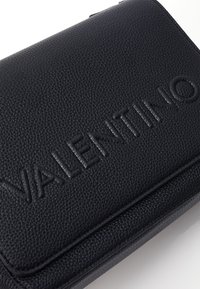 Borsa a tracolla in pelle nera texture con logo "VALENTINO" in rilievo, caratterizzata da una forma rettangolare elegante e da minimal accent hardware.