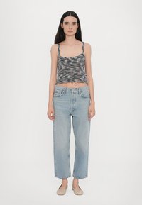 Grå og svart mønstrete ermeløs topp med en cropped design, parret med lyseblå høyhalsede rette jeans og nude leiligheter.
