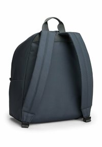Zaino grigio scuro con finitura testurizzata, spallacci imbottiti e maniglia superiore. Presenta un design minimalista senza loghi visibili.