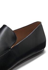 Schwarzer Leder-Slipper mit glatter Oberfläche und einfacher Naht, zeigt das innere hellbraune Futter und die flache Sohle.