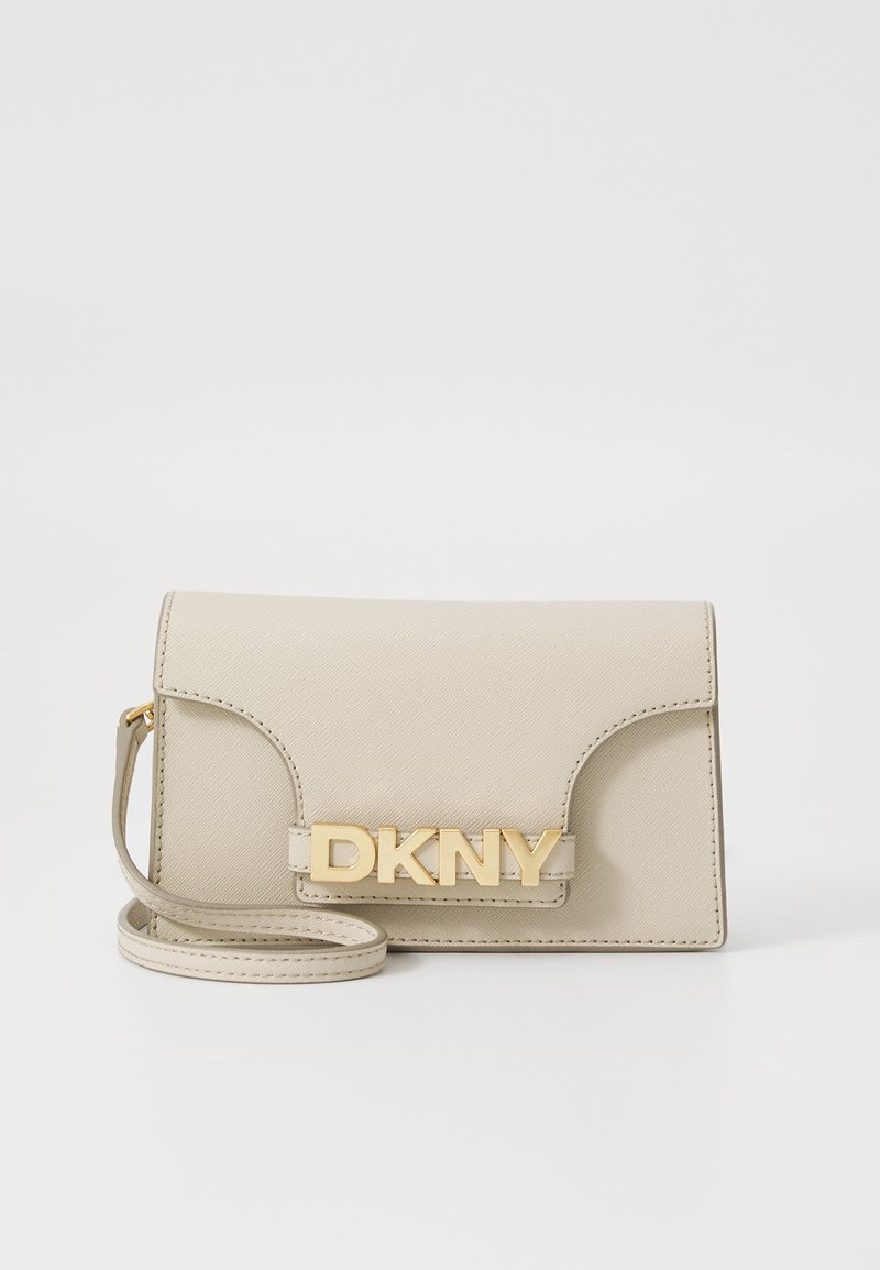Smėlio spalvos DKNY per petį nešama rankinė, pagaminta iš tekstūruoto medžiagos, su auksiniu logotipu, viršutine uždanga ir nuimama juosta. Stačiakampio formos.
