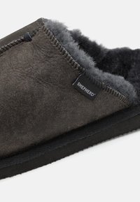 Dark gray slipper made from suede, featuring a soft inner lining, black rubber sole, and a visible brand tag on the side.