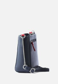 Navy blue vegan leather handbag with silver chain and red accents. Features a zip pocket and adjustable strap. Vertical design, smooth texture.