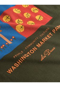 Graafinen puuvillakangas, jossa on kirkkaan sinisiä ja punaisia osia keltaisilla pyöreillä kuvioilla. Teksti "Washington Market Park" oranssilla.