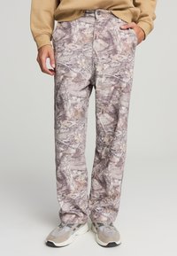 Pantaloni con motivo camouflage in tonalità di grigio e marrone, dotati di chiusura con bottone, design a gamba dritta e due tasche frontali.