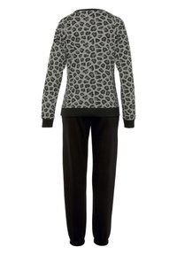Grå tröja med svart leopardmönster, rundad halsringning och långa ärmar; matchas med svarta, uppvikta sweatpants.