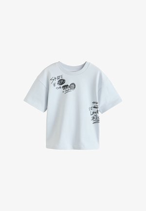 Hvid t-shirt med korte ærmer med sort håndskrevet tekst og grafik, der inkluderer "SKATE NYC", en globus og sætninger om skatingfærdigheder.