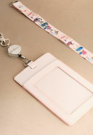 Světle růžový držák na karty s průhledným okénkem na průkaz připojeným k zatahovacímu šňůrce Cath Kidston s květinovými a šatními vzory.
