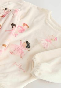 Cremefarbenes Sweatshirt- und Shorts-Set für Kinder, mit ballet-themed Illustrationen in Pink, gerüschten Ärmeln und Bund.