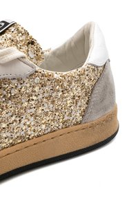 Sneaker glitterata oro e bianca con dettagli in suede, tomaia testurizzata, suola piatta in gomma e cuciture lungo il bordo.