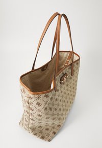 Sac fourre-tout beige avec un motif de logo marron, deux anses en cuir marron, ouverture en haut, et doublure intérieure affichant un motif de logo répétitif.