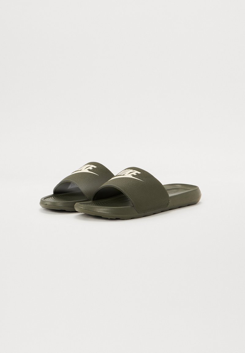 Chanclas verde oliva con tiras anchas y curvadas, superficie texturizada y logo en relieve. Suela flexible con patrón acanalado para un mejor agarre. Diseño ligero.