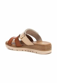 Sandalia de cuero marrón y beige con correas cruzadas, plantilla acolchada, suela con textura de madera y un ligero tacón. Forro interior suave y texturizado.