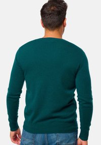 Dunkelgrüner Wollpullover mit rundem Ausschnitt, langen Ärmeln und glatter Textur, ausgestattet mit einer figurbetonten Passform und gerippten Bündchen.