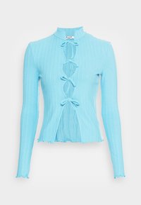 Blusa de manga longa azul clara com textura canelada, gola alta e detalhes de laço na frente. Apresenta uma bainha cropped e bordas desfiadas.
