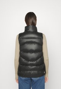 Gilet imbottito nero con colletto alto, caratterizzato da sezioni trapuntate e una superficie liscia. Progettato con una zip laterale e dettagli con logo.