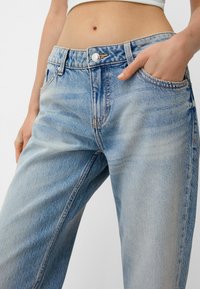 Lysblå cowboybukser med høj talje, der har knaplukning, forlommer og slidte detaljer for en afslappet pasform.