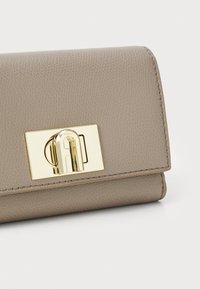 Gray textured leather wallet with a gold-tone clasp detailing, featuring a rectangular metal plate and precise stitching. Compact design.