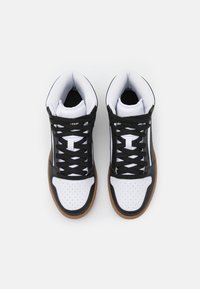 Wysokie sneakersy z czarną cholewką, białym noskiem z perforacjami, czarnymi sznurówkami i gumową podeszwą. Teksturowane białe wykończenie wewnętrzne.