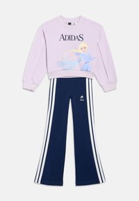 Ανοιχτό μωβ φούτερ Adidas με γραφικό της Ελσας από την ταινία Frozen, σε συνδυασμό με ναυτικά παντελόνια Adidas με λευκές ρίγες στο πλάι και λογότυπα.