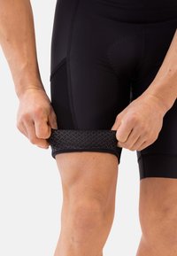 Shorts de compression noirs avec une bande élastique texturée au niveau de la cuisse. Conçus pour un ajustement optimal, avec des coutures plates et un tissu lisse.