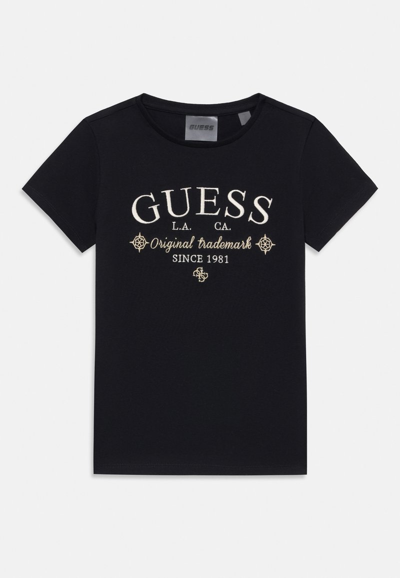 Črna bombažna majica s kratkimi rokavi, ki vsebuje belo vezeno besedilo "GUESS," "Original Trademark," in dekorativne akcentne elemente. Osnovni kroj s krožnim ovratnikom.