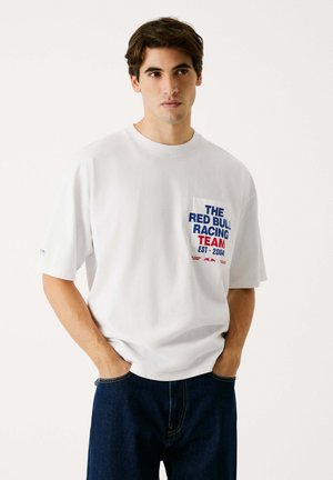 Witte katoenen T-shirt met korte mouwen, met een voorzak ontwerp bedrukt met "THE RED BULL RACING TEAM EST. 2004" in blauw en rood.
